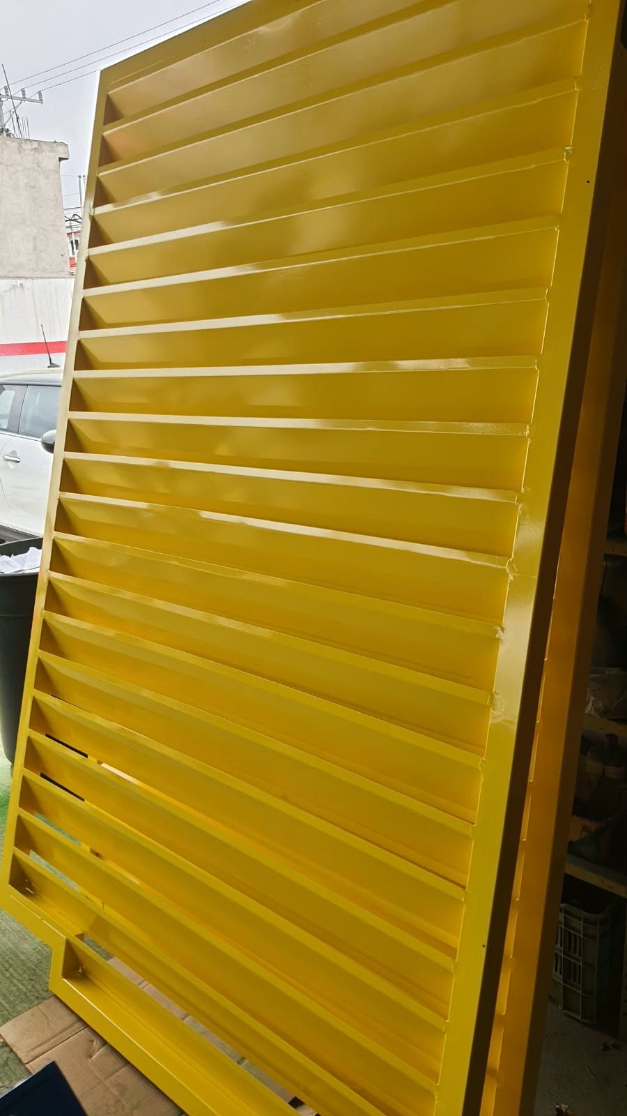 Panel de celosía metálica con pintura amarilla brillante recargado contra la pared