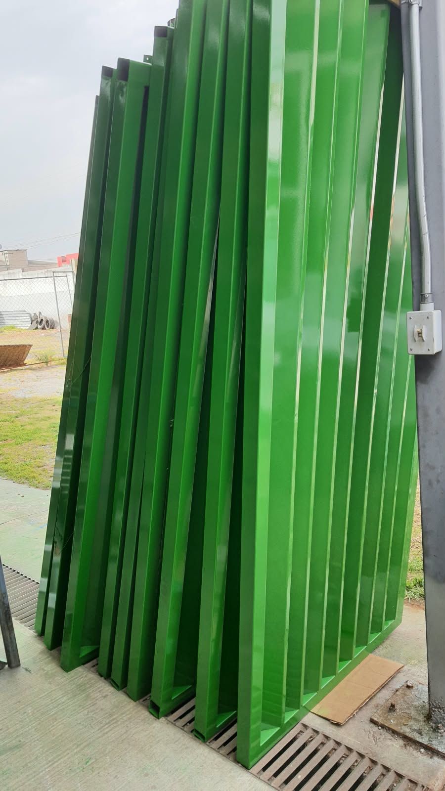 Marcos y perfiles de acero con acabado verde brillante recargados en una pared