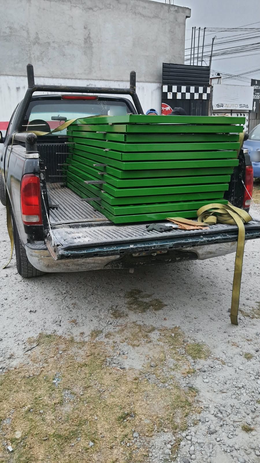 Marcos metálicos con pintura verde apilados y amarrados en la caja de una camioneta